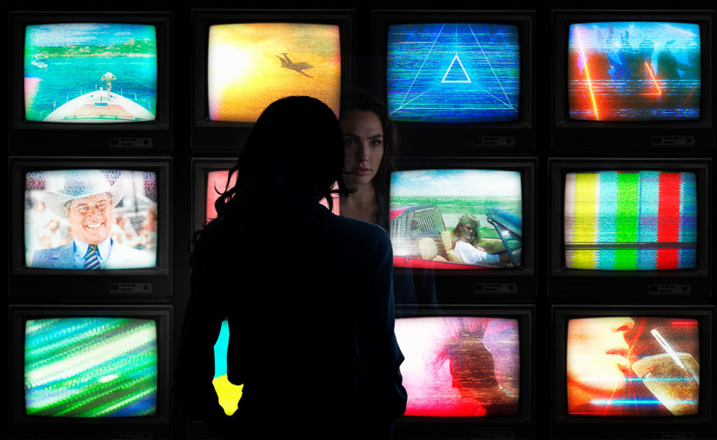 Gal Gadot in front of a screen of TVs in WONDER WOMAN 1984