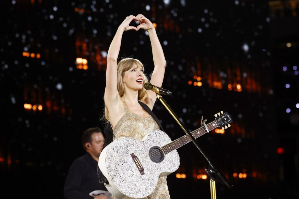 Taylor Swift holds her hands in a heart above her head during the Fearless portion of The Eras Tour