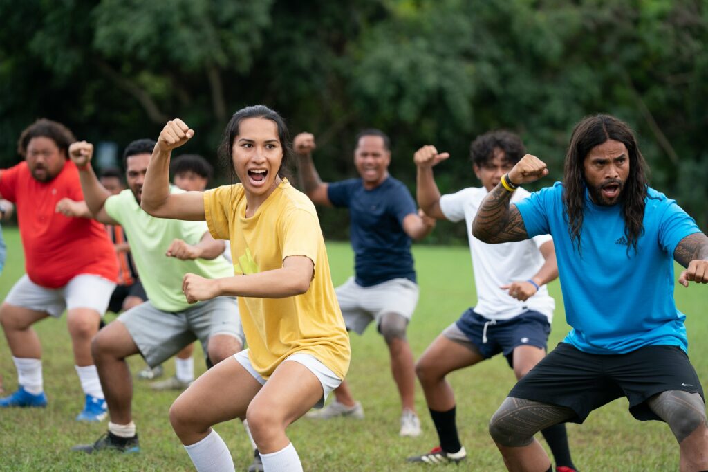 The cast, including Kaimana, prepares for a soccer match in NEXT GOAL WINS (2023)